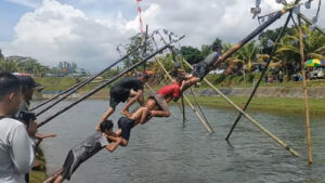 Peserta lomba panjat pinang tengah berjuang.